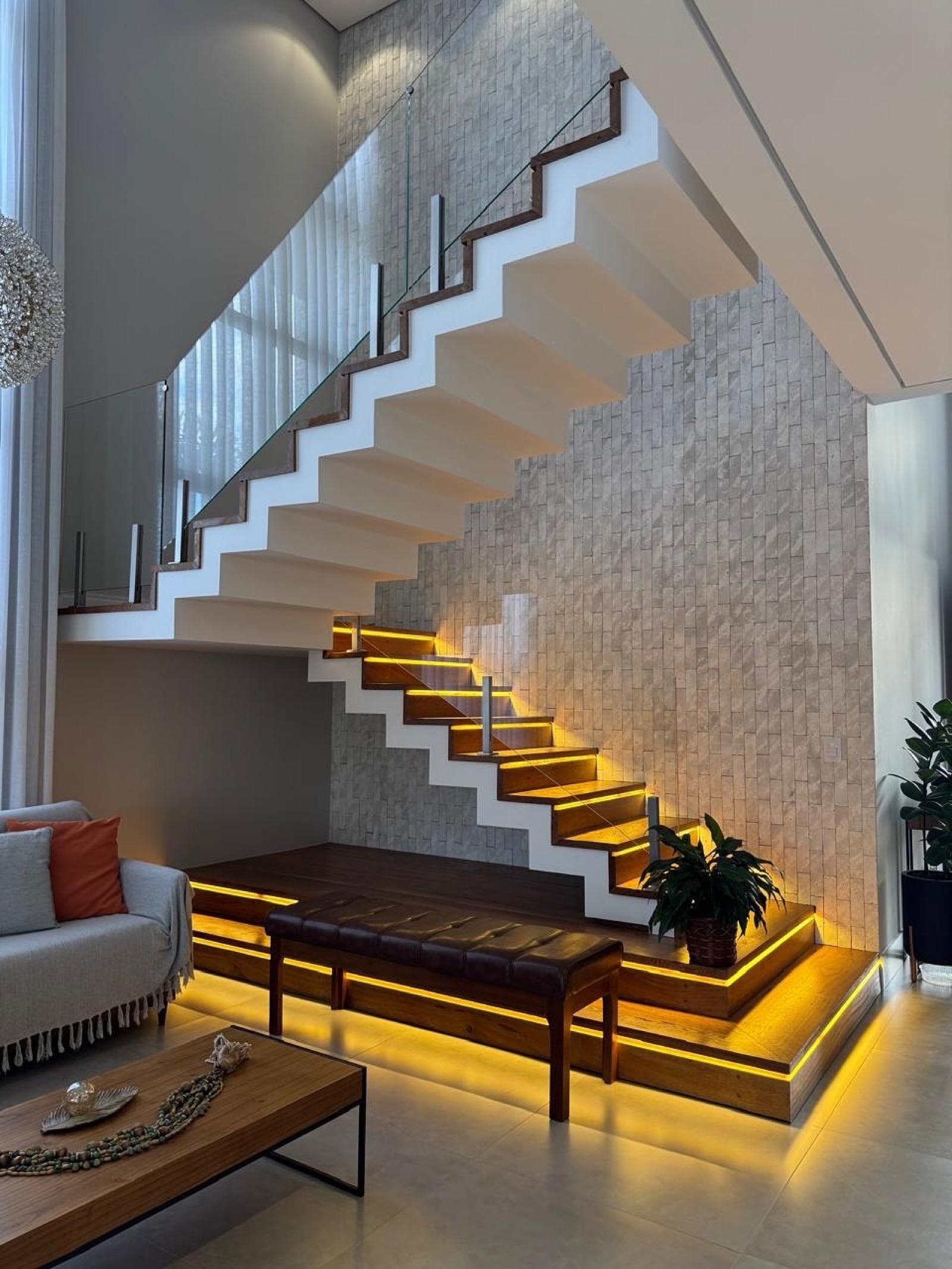 Escada iluminada e estar integrado com marcenaria e iluminação de destaque